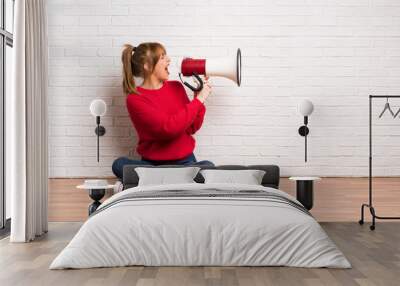 Redhead woman siting on the floor shouting through a megaphone Wall mural