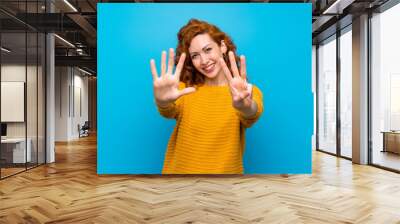 Redhead woman with yellow sweater counting eight with fingers Wall mural