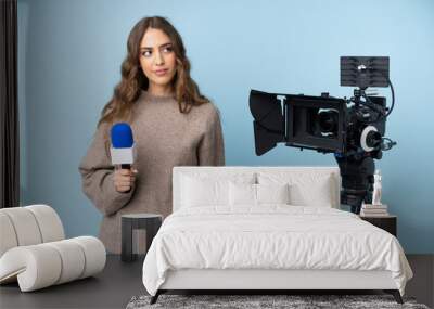 Reporter young woman holding a microphone and reporting news standing and looking to the side Wall mural