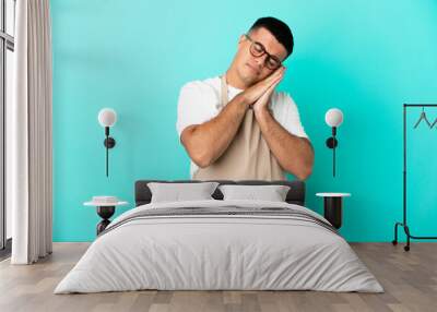 Restaurant waiter man over isolated blue background making sleep gesture in dorable expression Wall mural