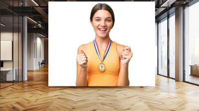 Teenager caucasian girl with medals over isolated background celebrating a victory in winner position Wall mural