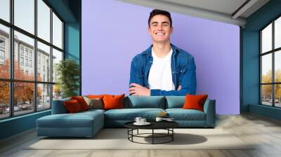 Teenager caucasian  handsome man isolated on purple background keeping the arms crossed in frontal position Wall mural