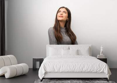 Teenager girl on isolated white backgorund looking up while smiling Wall mural