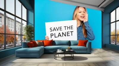 Teenager girl over isolated blue background holding a placard with text Save the Planet and shouting Wall mural