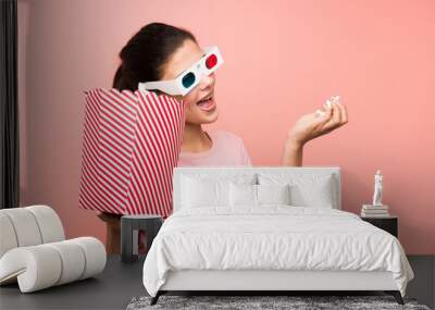 Teenager girl over isolated pink wall eating popcorns with 3d glasses Wall mural