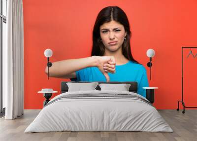 Teenager girl with blue shirt showing thumb down sign Wall mural