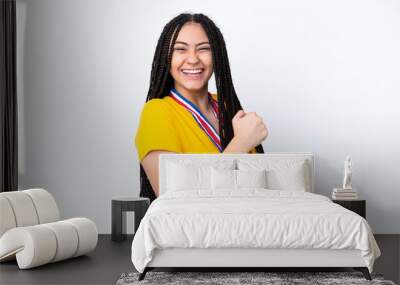 Teenager girl with braids and medals over isolated pink background celebrating a victory Wall mural