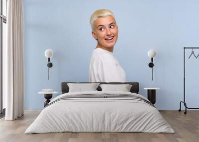 Teenager girl with white short hair over blue wall with arms crossed and happy Wall mural