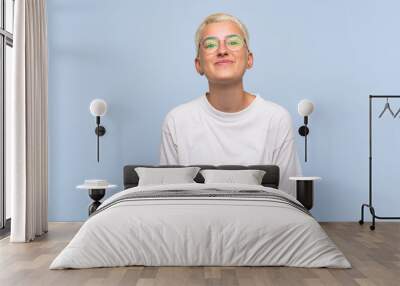 Teenager girl with white short hair over blue wall with glasses and smiling Wall mural