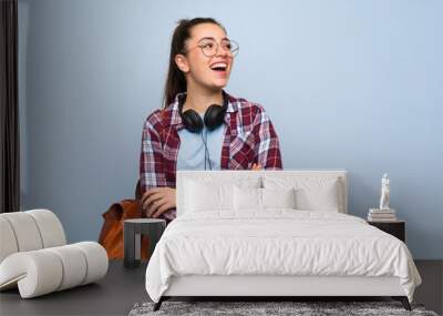 Teenager student girl over isolated blue wall happy and smiling Wall mural