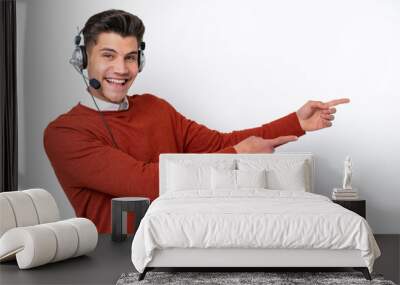 Telemarketer caucasian man working with a headset isolated on white background pointing finger to the side and presenting a product Wall mural