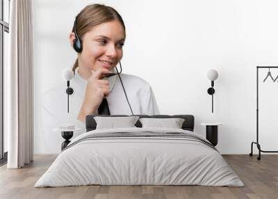 Telemarketer caucasian woman working with a headset over isolated background thinking an idea and looking side Wall mural