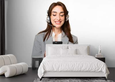 Telemarketer caucasian woman working with a headset over isolated chroma key background sending a message with the mobile Wall mural