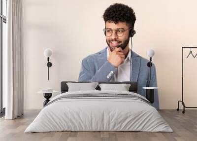 Telemarketer Moroccan man working with a headset isolated on beige background looking to the side and smiling Wall mural