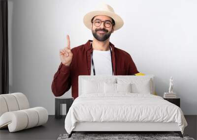 Traveler man man with beard holding a suitcase over isolated white background showing and lifting a finger in sign of the best Wall mural