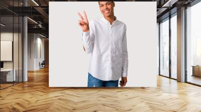 Young african american man smiling and showing victory sign with a cheerful face on grey background Wall mural