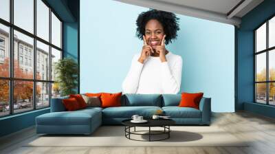 Young African American woman isolated on blue background smiling with a happy and pleasant expression Wall mural