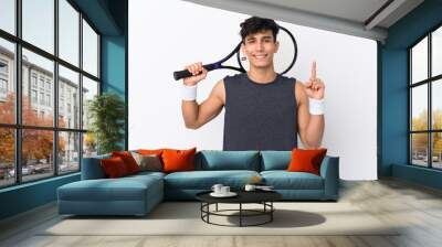 Young Argentinian man over isolated white background playing tennis and pointing up Wall mural