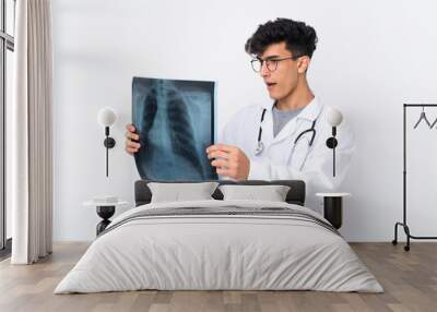 Young Argentinian man over isolated white background wearing a doctor gown and holding a bone scan Wall mural