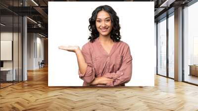 Young Argentinian woman over isolated background holding copyspace imaginary on the palm to insert an ad Wall mural