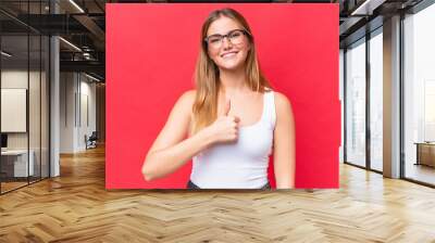 Young beautiful woman isolated on red background giving a thumbs up gesture Wall mural