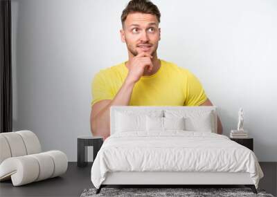 Young blonde caucasian man isolated on white background thinking an idea while looking up Wall mural