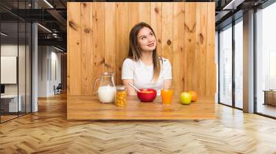 Young blonde woman having breakfast laughing and looking up Wall mural