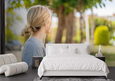 Young blonde woman holding a bowl of fruit at outdoors in back position Wall mural