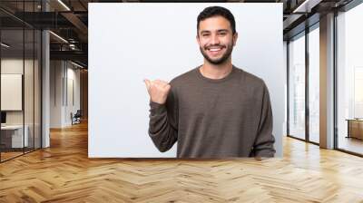 Young Brazilian man isolated on white background pointing to the side to present a product Wall mural