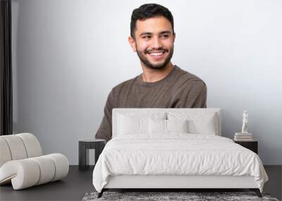 Young Brazilian man isolated on white background with arms crossed and happy Wall mural