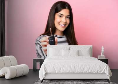 Young Brazilian woman holding car keys isolated on pink background with happy expression Wall mural