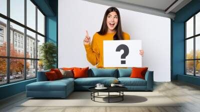 Young Brazilian woman isolated on white background holding a placard with question mark symbol and thinking Wall mural