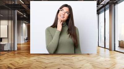 Young Brazilian woman isolated on white background looking up while smiling Wall mural