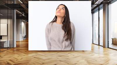 Young brunette woman over isolated white background and looking up Wall mural