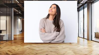 Young brunette woman over isolated white background looking up while smiling Wall mural