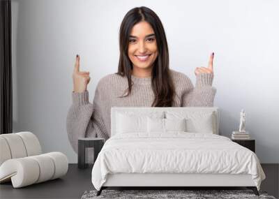 Young brunette woman over isolated white background pointing up a great idea Wall mural