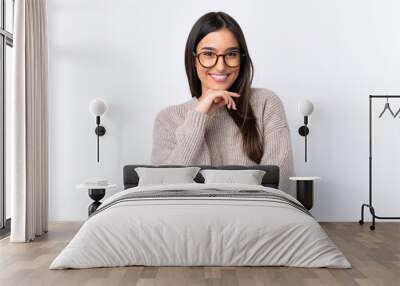 Young brunette woman over isolated white background with glasses and smiling Wall mural