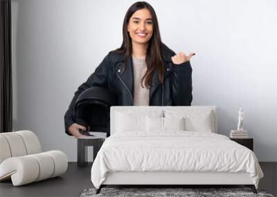 Young brunette woman with a motorcycle helmet over isolated white background pointing to the side to present a product Wall mural