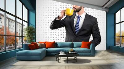 Young businessman drinking a coffee over background with icons Wall mural