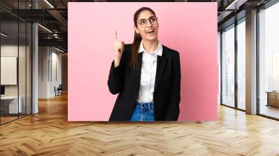 Young caucasian business woman isolated on pink background pointing up and surprised Wall mural