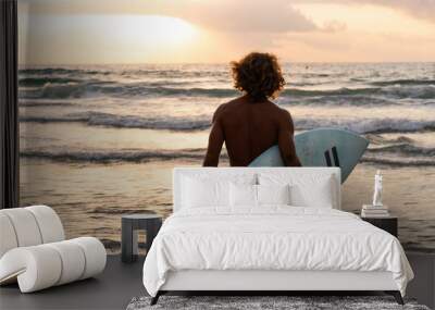 Young caucasian man get up early to  doing surf at sunrise Wall mural