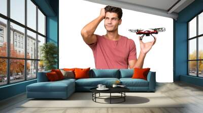 Young caucasian man holding a drone over isolated background having doubts and with confuse face expression Wall mural