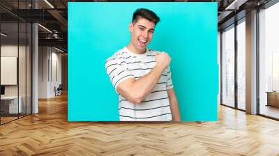 Young caucasian man isolated on blue background celebrating a victory Wall mural