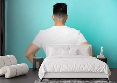 Young caucasian man isolated on blue background in back position Wall mural