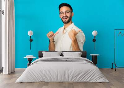 Young caucasian man isolated on blue background pointing to the side to present a product Wall mural