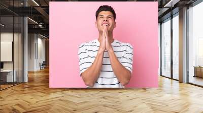 Young caucasian man isolated on pink background keeps palm together. Person asks for something Wall mural