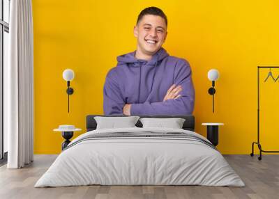 Young caucasian man isolated on yellow background keeping the arms crossed in frontal position Wall mural