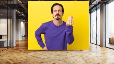 Young caucasian man isolated on yellow background making Italian gesture Wall mural