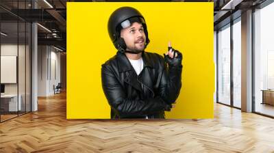 Young caucasian man with a motorcycle helmet isolated on yellow background pointing up a great idea Wall mural