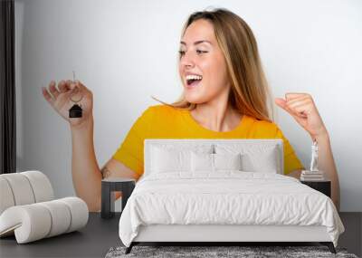 Young caucasian woman holding home keys isolated on white background celebrating a victory Wall mural